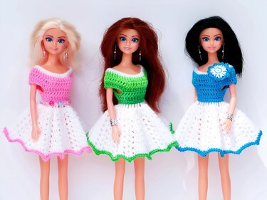 Drei Modepuppen in gehäkelten Kleidern mit weißem Rock und farbigen Oberteilen (rosa, grün, blau)