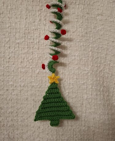 Gehäkelter grüner Weihnachtsbaum-Anhänger mit weißer Spiralgirlande, roten Akzenten und gelbem Stern