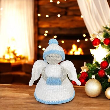 Gehäkeltes Amigurumi-Engelchen in Weiß mit hellblauen Details vor Weihnachtsbaum und Kaminlicht
