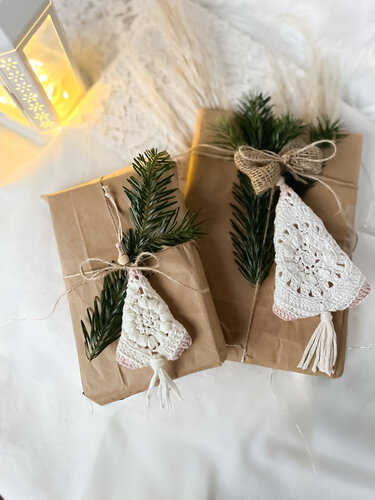 Zwei braun verpackte Geschenke mit Tannenzweigen und gehäkelten Granny‑Bäumen