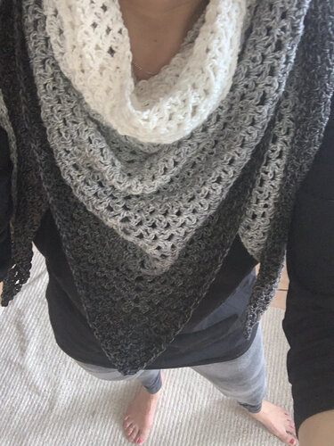 Gehäkeltes Dreieckstuch in Grau- und Weißtönen mit offenem Muster, getragen am Hals