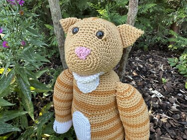 Nahaufnahme gestreifte Amigurumi-Katze mit rosa Nase und weißen Applikationen