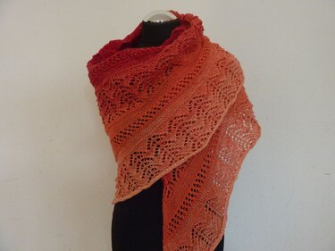 Rot‑oranges Lacetuch mit Farbverlauf und feinem Lochmuster auf schwarzer Schneiderpuppe