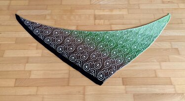 Gestricktes Dreieckstuch mit Paisley
‑Muster in Braun
‑Grün auf Parkett