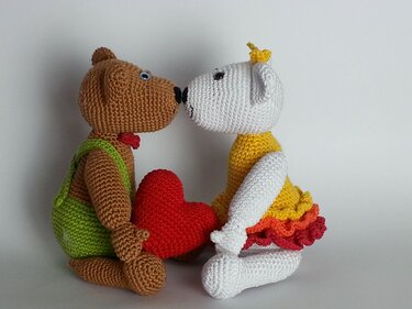 Zwei gehäkelte Amigurumi-Bären, ein brauner und ein weißer, mit einem roten Herz
