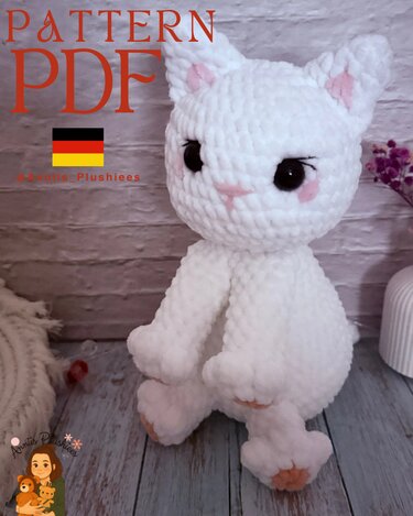 Weißes gehäkeltes Amigurumi-Kätzchen mit rosa Details vor hellem Hintergrund