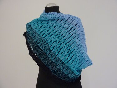 Gehäkelter Loop mit Ombré‑Farbverlauf in Blau‑ und Türkistönen auf schwarzer Schneiderpuppe