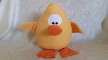 Gelbes genähtes Kuscheltier in Form eines Küken mit orange Schnabel und Füßen