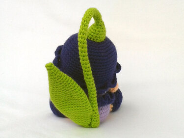 Dark blue crocheted amigurumi doll seen from the back with a bright green leaf and top loop.