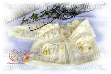 Cremefarbene gestrickte Babyjacke mit gelben Knöpfen und aufgesetzten Taschen