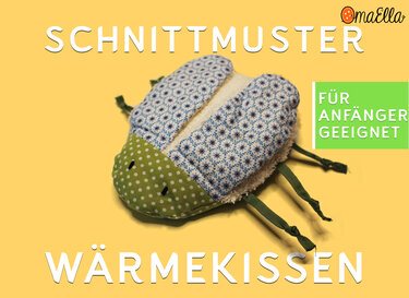 Genähtes Käfer-Wärmekissen aus grünem gepunktetem Stoff und blauem Blumenstoff auf gelbem Hintergrund.