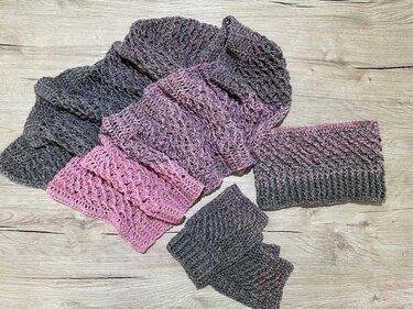 Gehäkelter Schal, Stirnband und Pulswärmer aus Grau-Rosa Verlaufsgarn auf hellem Holzboden