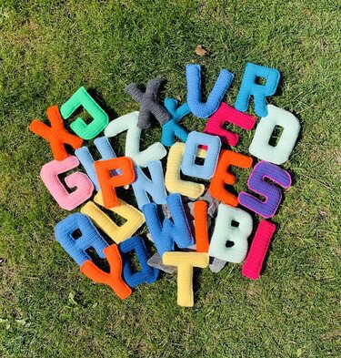 Pile of bright, colorful crocheted alphabet letters on grass