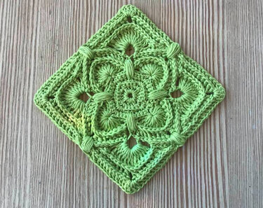 Hellgrünes gehäkeltes Granny-Quadrat mit Büschelmaschen auf Holzuntergrund