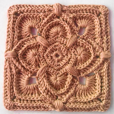 Gehäkeltes quadratisches Granny Square in Pfirsich mit erhabenen Zopf- und Reliefmustern