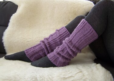 Violette gestrickte Beinstulpen über dunkler Strumpfhose, Seitenansicht der Beine