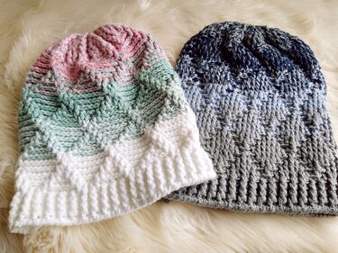 Zwei gehäkelte Mützen mit Rippenbündchen und diagonalem Zopfmuster in Pastell und Graublau