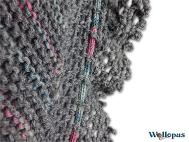 Nahaufnahme eines gestrickten Musters in Grau mit rosa und hellblauen Streifen und einem Lochrand.