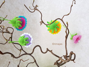 Kleine, schnell gehäkelte Blumen mit gezackten Rändern an dekorativen, gedrehten Zweigen