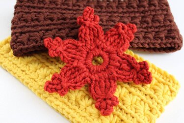 Rote gehäkelte Blatt-Applikation auf gelbem Stirnband, braunes Häkelstück im Hintergrund