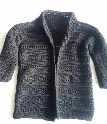 Schwarze gehäkelte Jacke mit Stehkragen und langen Ärmeln, auf hellem Untergrund
