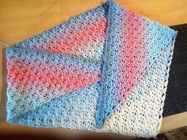 Folded pastel gradient crochet triangle shawl with lacy cluster stitch in blue, pink and cream