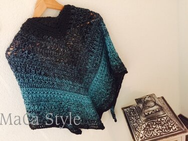 Gehäkelter Poncho mit Ombré-Farbverlauf von Dunkel zu Türkis an Holzbügel