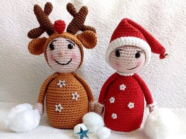 Zwei gehäkelte Amigurumi-Puppen: links braunes Rentier mit Geweih, rechts rote Wichtelpuppe mit Zipfelmütze, davor Wattebällchen und kleine Deko