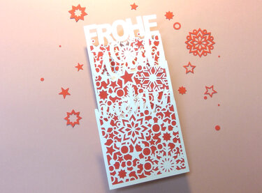 Zweilagige Plottkarte mit ausgeschnittener „Frohe Weihnachten“-Schrift, weißen Schneeflocken und rotem Hintergrund