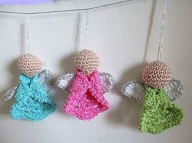 Drei gehäkelte Engel in Türkis, Pink und Grün mit funkelnden Flügeln an einer Schnur
