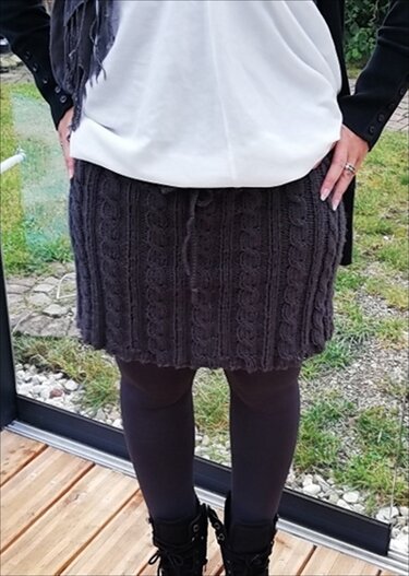 Dunkelgrauer gestrickter Minirock mit Zopfmuster und Kordelzug über dunklen Leggings und Schnürstiefeln
