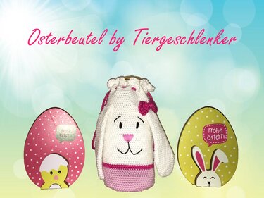 Weiß-rosa gehäkelter Osterbeutel in Hasenform mit pinker Schleife und Kordelzug, daneben zwei dekorative Ostereier mit Küken- und Hasenmotiv.