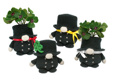 Four crocheted chimney sweep figures in black suits and top hats, with ribbons and a shamrock or decorative four-leaf clovers.
