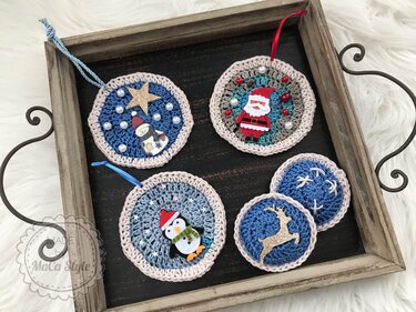Runde gehäkelte Weihnachtsanhänger mit Schneemann, Weihnachtsmann, Pinguin und Rentier in einem Holztablett