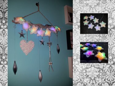 Hängedekoration aus Ast mit leuchtenden gehäkelten Sternen, geflochtenem Herz und silbernen Ornamenten vor türkisfarbener Wand.