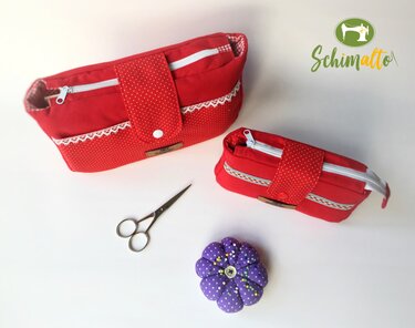 Zwei rote Utensilo-Taschen, Nähschere und violettes Nadelkissen