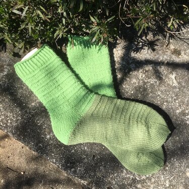 Nahaufnahme hellgrüner Socken mit Rippenbündchen und glatt gestricktem Fuß