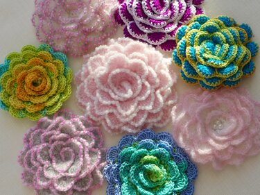Verschiedene kleine gehäkelte Blumenapplikationen in Pastell- und kräftigen Farben