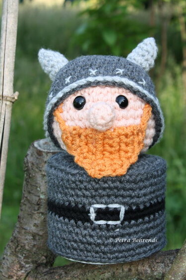 Gehäkelter Zwerg mit Wikingerhelm und orangefarbenem Bart auf Baumstumpf