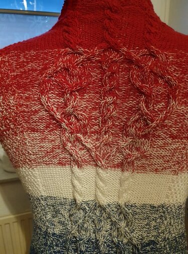 Rückendetail einer gestrickten Jacke mit herzförmigen Zöpfen und Farbverlauf