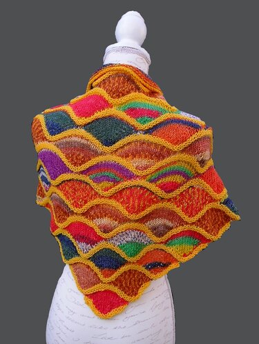 Gestricktes, buntes Dreieckstuch mit Schuppenmuster und senfgelben Rändern auf einer Schaufensterpuppe.