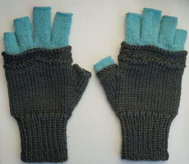 Paar gestrickter Halbfingerhandschuhe dunkelgrau mit türkisen Fingern, flach nebeneinander gelegt