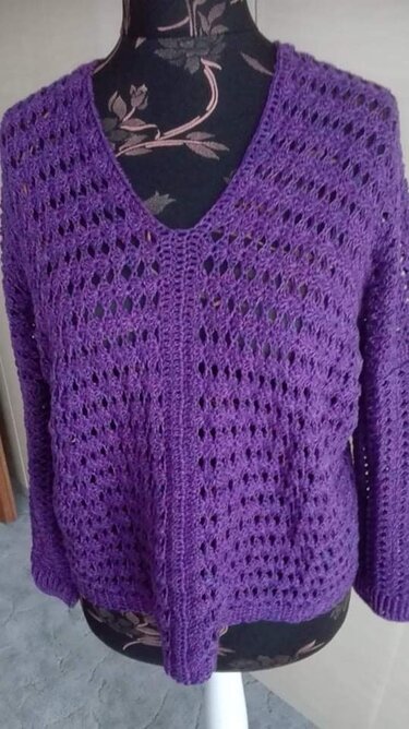 Lila gehäkelter Damenpullover mit V-Ausschnitt und offenem Lochmuster auf einer Schneiderpuppe.