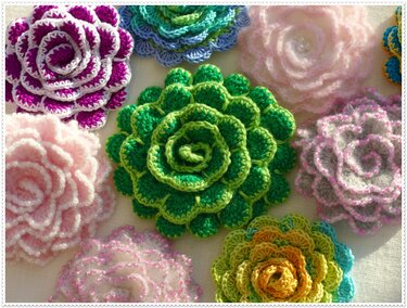 Nahaufnahme verschiedener gehäkelter Blumenapplikationen mit geschichteten Blütenblättern