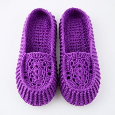 Pair of purple crocheted women's slippers with an openwork decorative toe and ribbed edges on a light background.