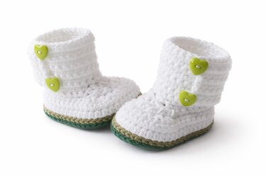 Weiß gehäkelte Babyschuhe mit grünen Herzknöpfen und olivgrün-dunkelgrüner Sohle