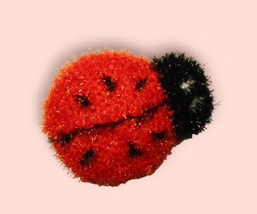 Roter gehäkelter Marienkäfer-Spülschwamm mit schwarzem Kopf und Punkten
