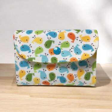 Rechteckige Utensilo-Tasche aus bedrucktem Stoff mit bunten Vögeln und blauem Druckknopf