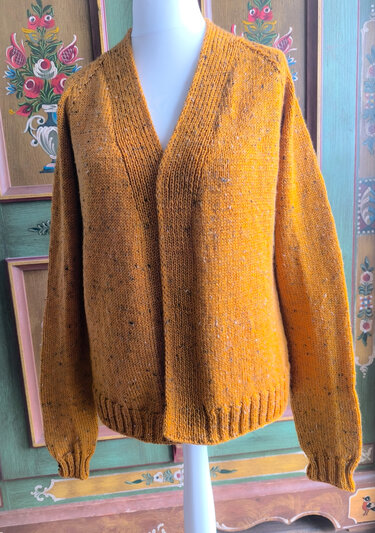 Senfgelbe, gesprenkelte Strickjacke mit offenem Schnitt auf weißer Schneiderpuppe