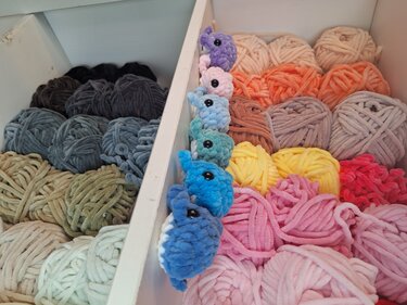 Sechs kleine gehäkelte Mini-Wale in verschiedenen Farben auf sortierten Chenille-Garnknäueln